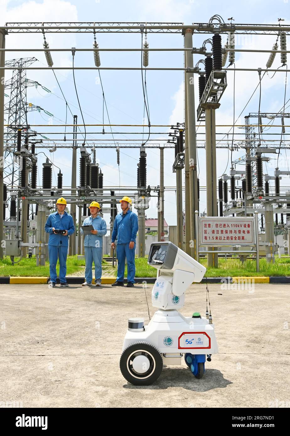 CHUZHOU, CHINE - 8 AOÛT 2023 - Un robot intelligent 5G et du personnel d'exploitation et de maintenance inspectent l'équipement d'alimentation électrique dans une sous-station de 220 kV Banque D'Images