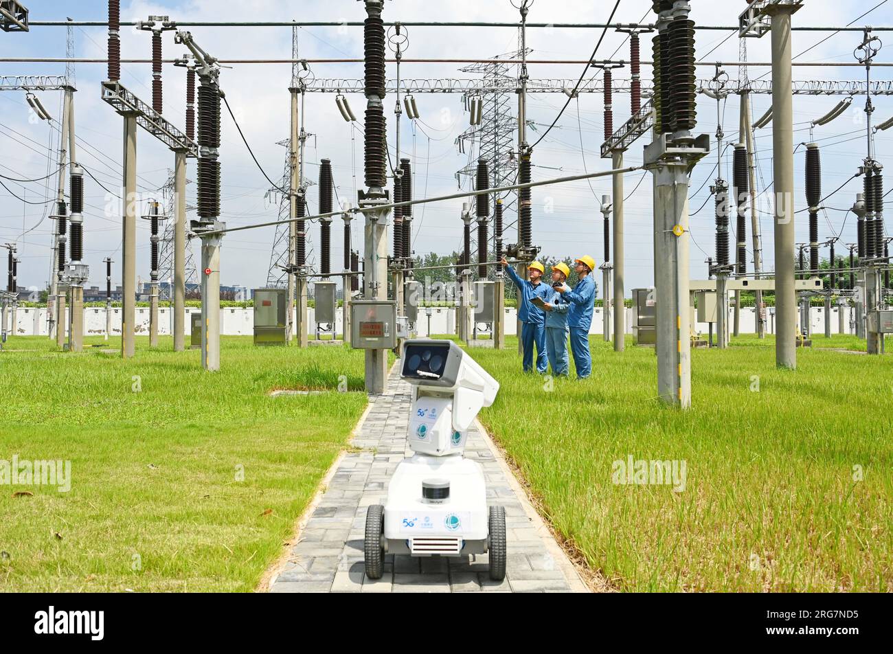 CHUZHOU, CHINE - 8 AOÛT 2023 - Un robot intelligent 5G et du personnel d'exploitation et de maintenance inspectent l'équipement d'alimentation électrique dans une sous-station de 220 kV Banque D'Images