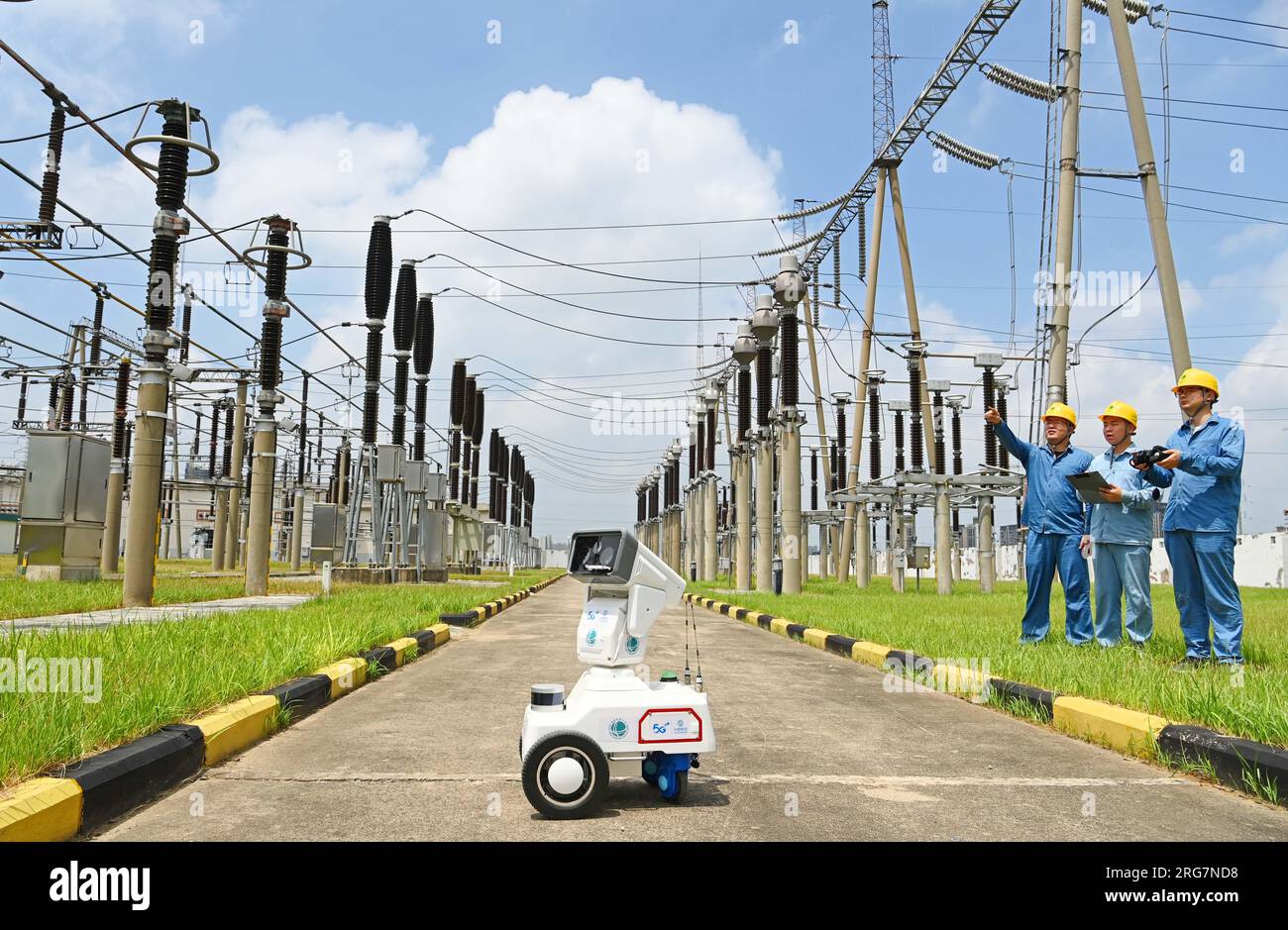 CHUZHOU, CHINE - 8 AOÛT 2023 - Un robot intelligent 5G et du personnel d'exploitation et de maintenance inspectent l'équipement d'alimentation électrique dans une sous-station de 220 kV Banque D'Images