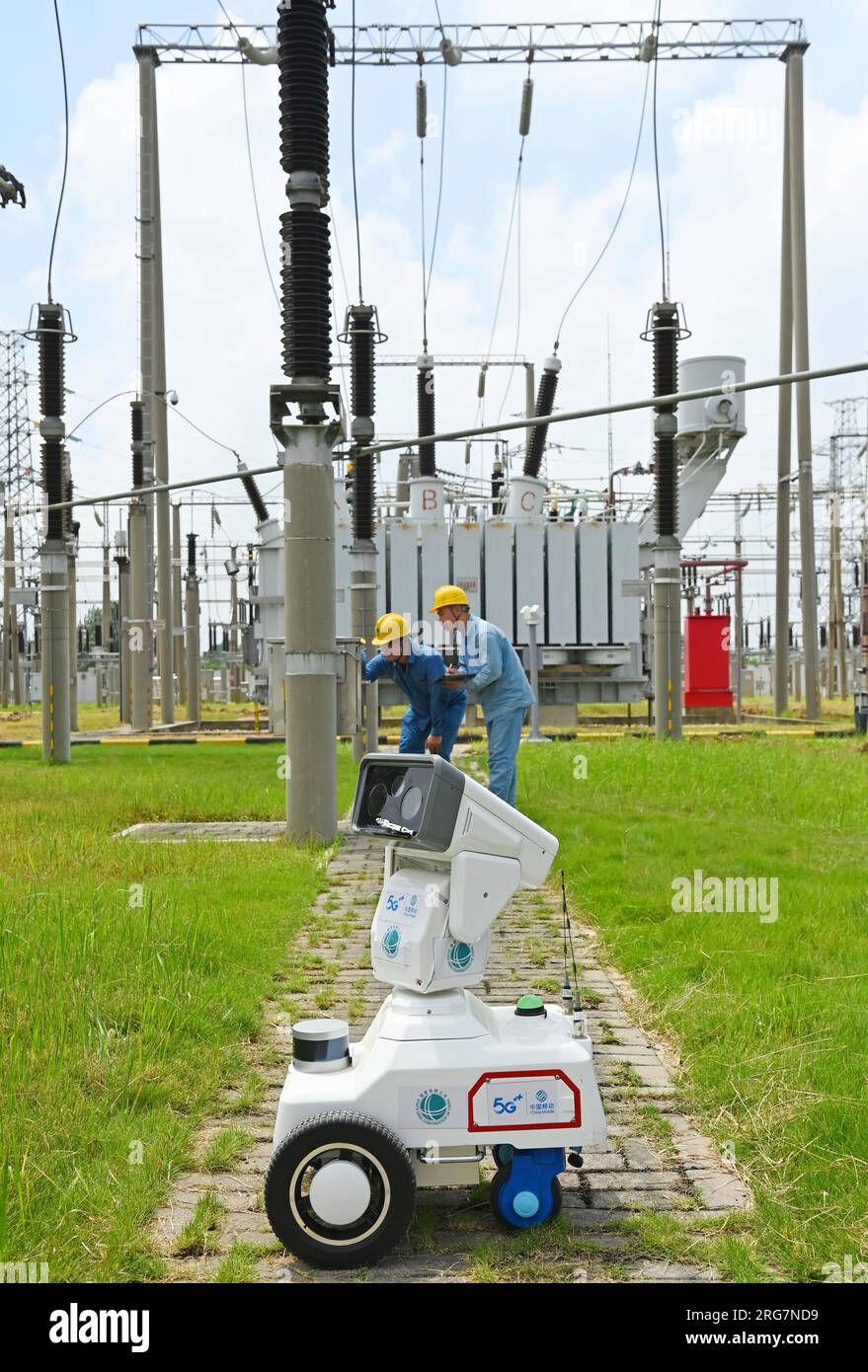 CHUZHOU, CHINE - 8 AOÛT 2023 - Un robot intelligent 5G et du personnel d'exploitation et de maintenance inspectent l'équipement d'alimentation électrique dans une sous-station de 220 kV Banque D'Images