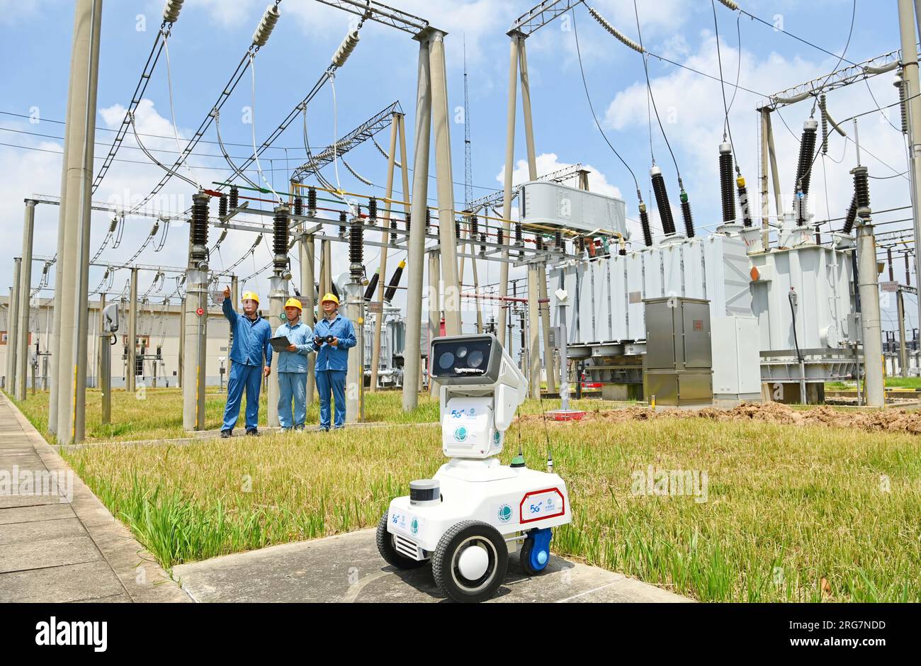 CHUZHOU, CHINE - 8 AOÛT 2023 - Un robot intelligent 5G et du personnel d'exploitation et de maintenance inspectent l'équipement d'alimentation électrique dans une sous-station de 220 kV Banque D'Images