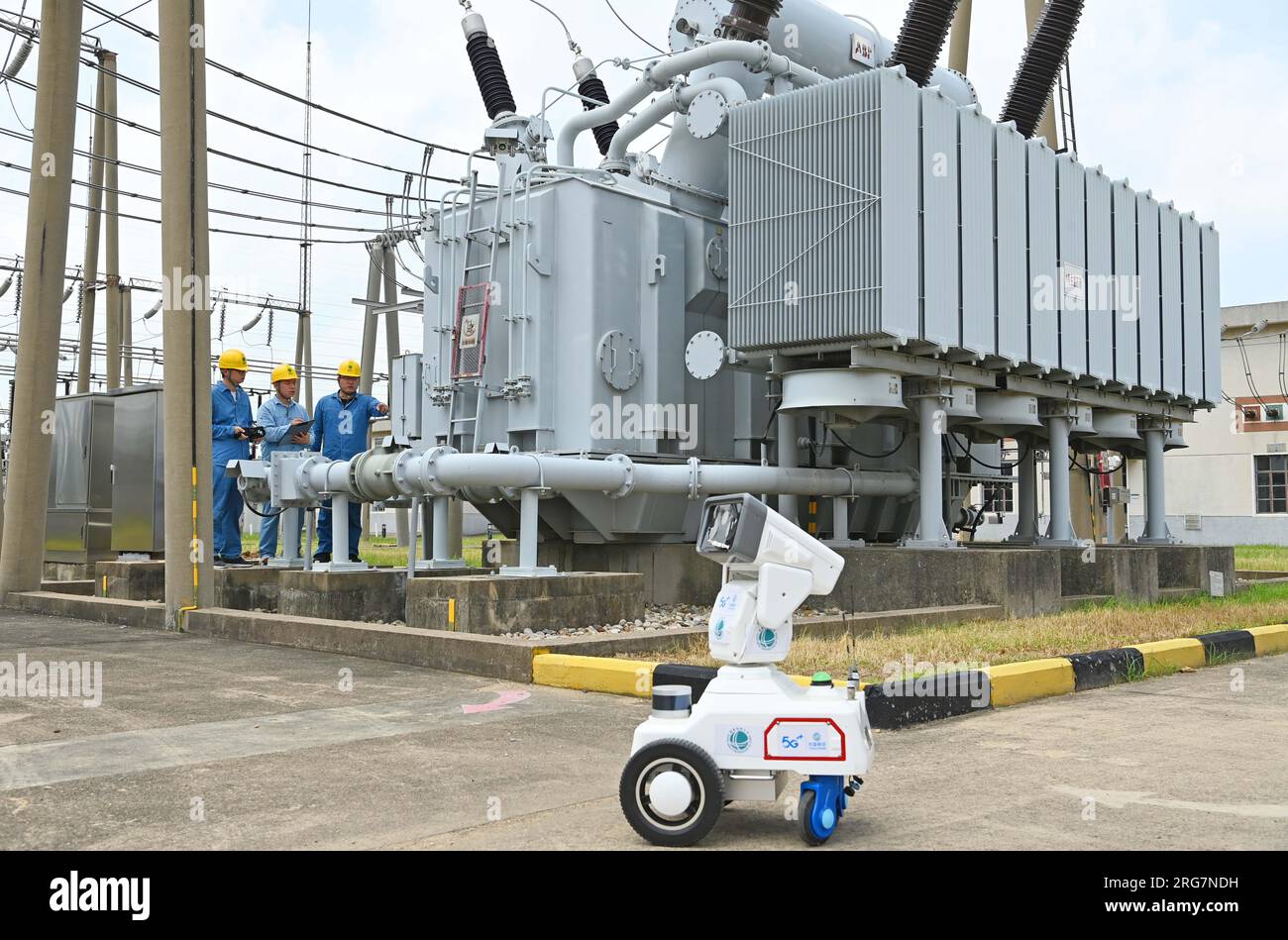 CHUZHOU, CHINE - 8 AOÛT 2023 - Un robot intelligent 5G et du personnel d'exploitation et de maintenance inspectent l'équipement d'alimentation électrique dans une sous-station de 220 kV Banque D'Images