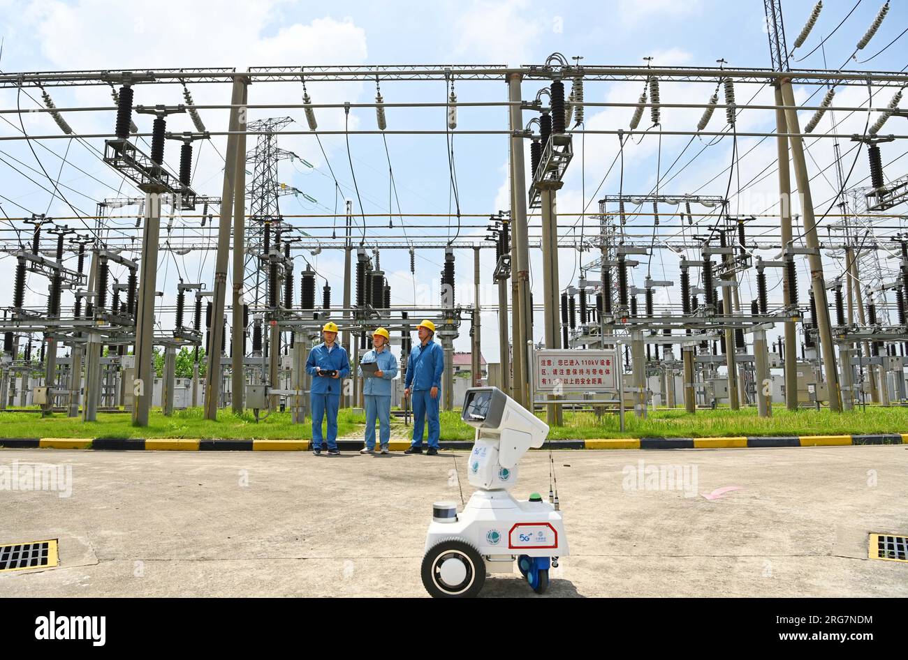 CHUZHOU, CHINE - 8 AOÛT 2023 - Un robot intelligent 5G et du personnel d'exploitation et de maintenance inspectent l'équipement d'alimentation électrique dans une sous-station de 220 kV Banque D'Images