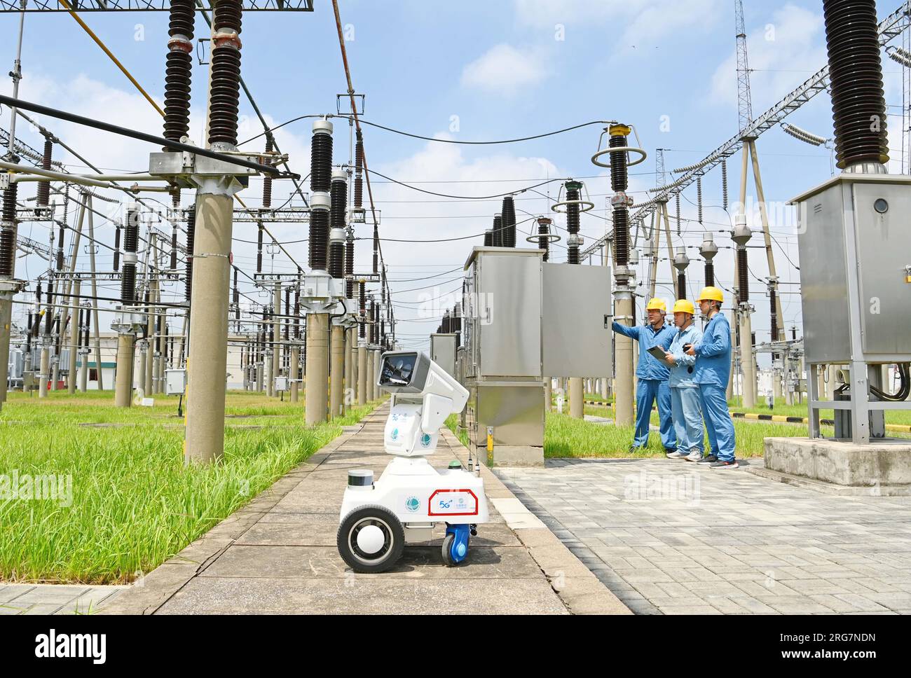 CHUZHOU, CHINE - 8 AOÛT 2023 - Un robot intelligent 5G et du personnel d'exploitation et de maintenance inspectent l'équipement d'alimentation électrique dans une sous-station de 220 kV Banque D'Images