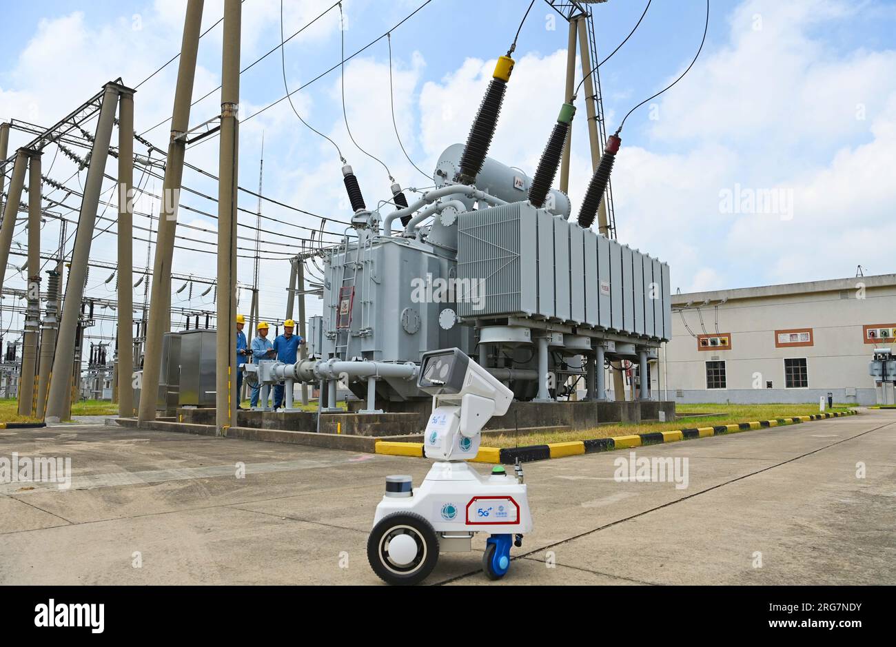 CHUZHOU, CHINE - 8 AOÛT 2023 - Un robot intelligent 5G et du personnel d'exploitation et de maintenance inspectent l'équipement d'alimentation électrique dans une sous-station de 220 kV Banque D'Images