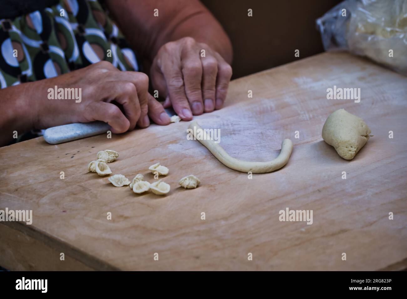 Gros plan sur les mains d'une femme préparant orecchiette, les pâtes typiques des pouilles, dans la rue du centre-ville de Bari Banque D'Images