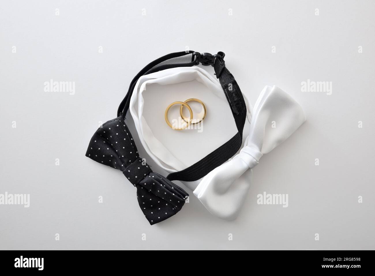 Fond de mariage gay conceptuel avec noeud papillon noir et blanc formant un cercle et des anneaux de mariage au centre. Vue de dessus. Banque D'Images