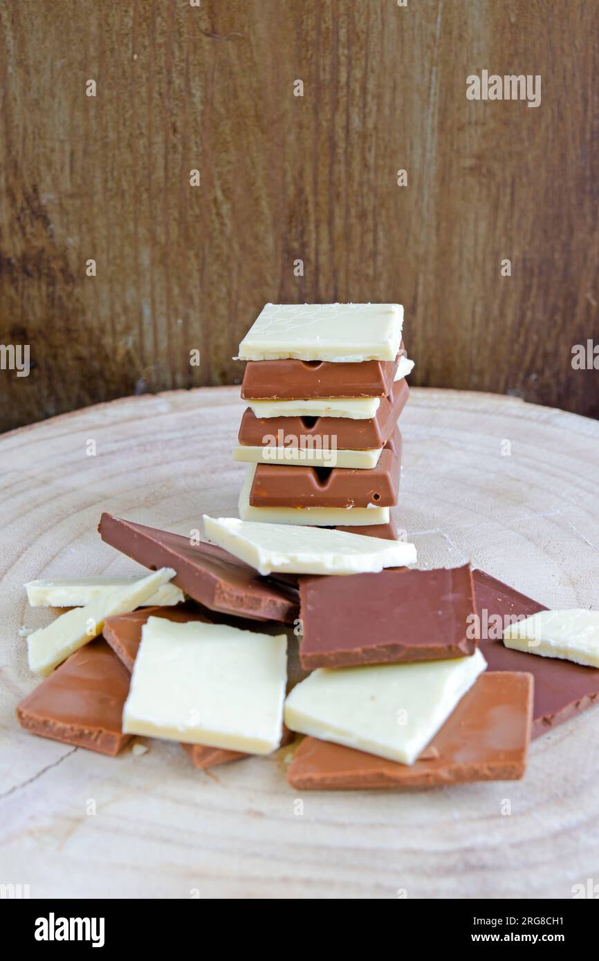 Barres de chocolat blanc, lait et noir formant une pile sur une base en bois. Tir vertical. Banque D'Images