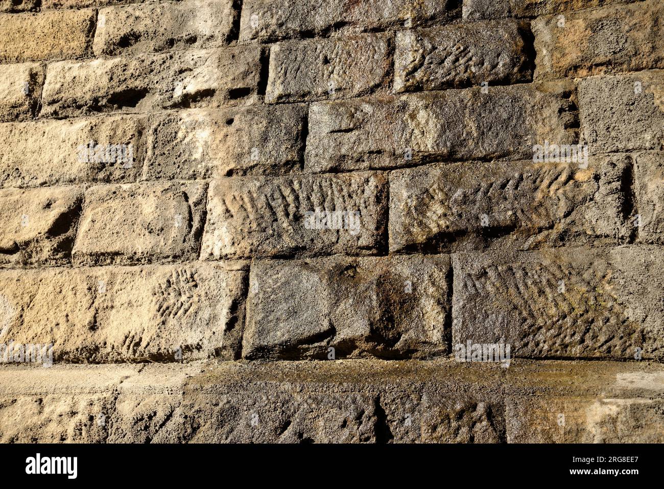 Une surface texturée de blocs de granit pour former un mur. Un peu d'eau de surface humide. Une image d'arrière-plan peut-être. Banque D'Images
