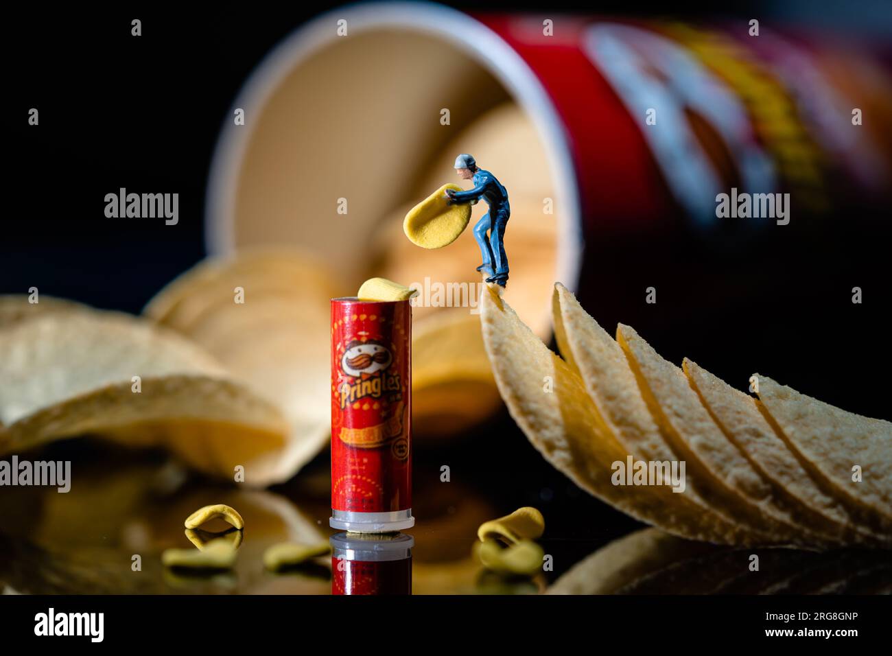 Pringles travailleur miniature emballe (ou déballe) un petit paquet de Pringles Banque D'Images