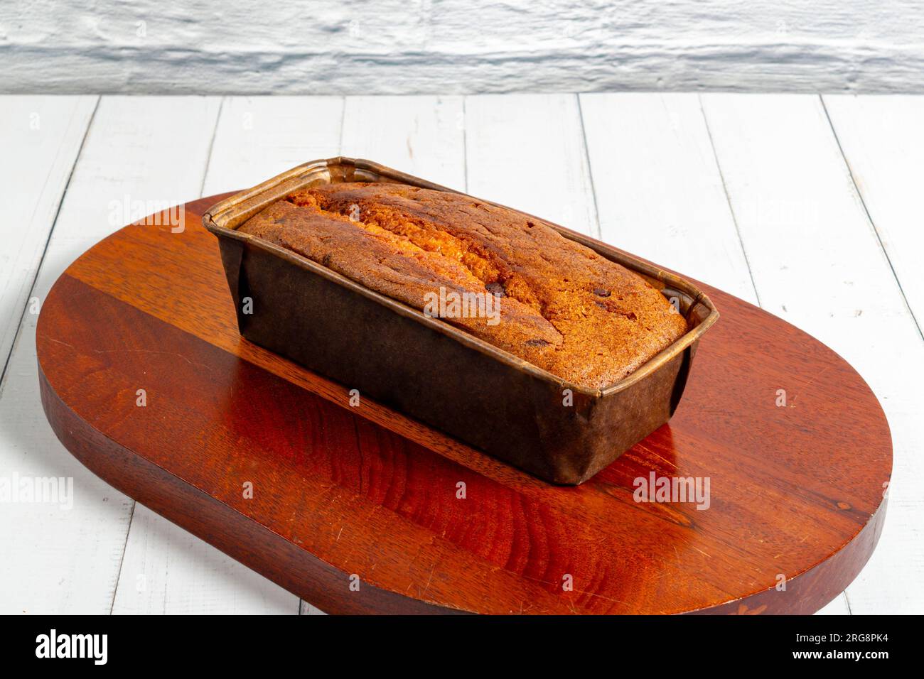Un gâteau anglais dans un plat allant au four sur une planche de bois et une table en bois blanc. Mise au point sélective Banque D'Images