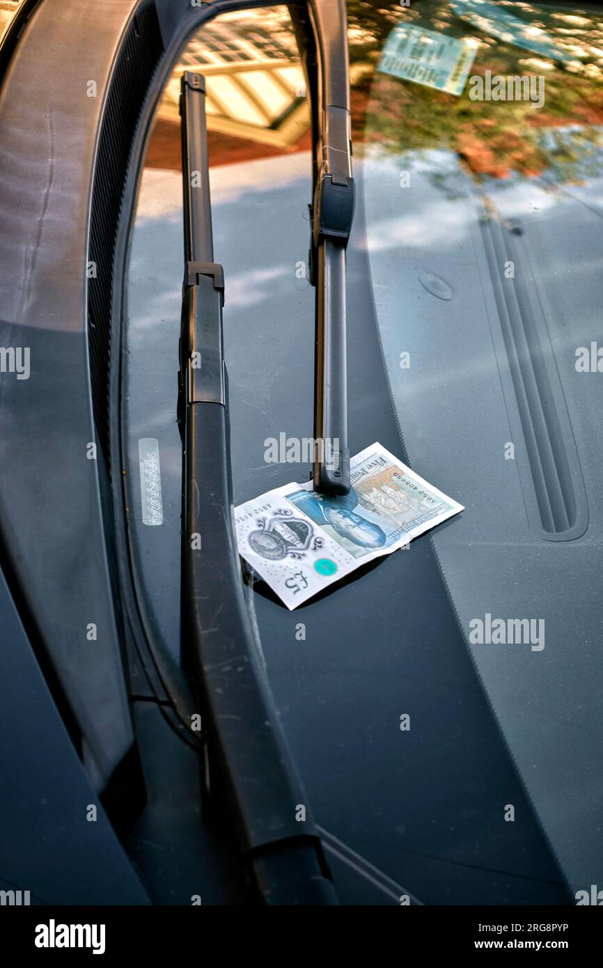 Concept de corruption. billet de 5,00 £ épinglé sous un essuie-glace de voiture. Angleterre Royaume-Uni Banque D'Images Concept de corruption. billet de 5,00 £ épinglé sous un essuie-glace de voiture. Angleterre Royaume-Uni Banque D'Images