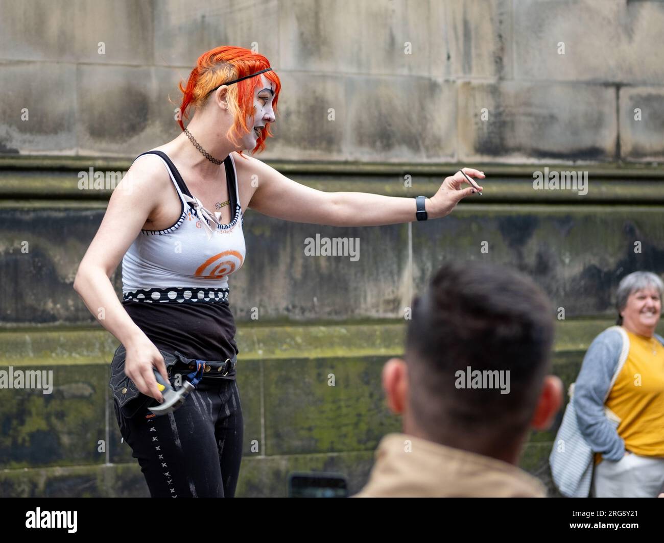 Une artiste de rue exécute son acte «Gory» de marteler des clous dans son nez, sur le Royal Mile, Édimbourg pendant le Fringe Festival, août 2023. Banque D'Images