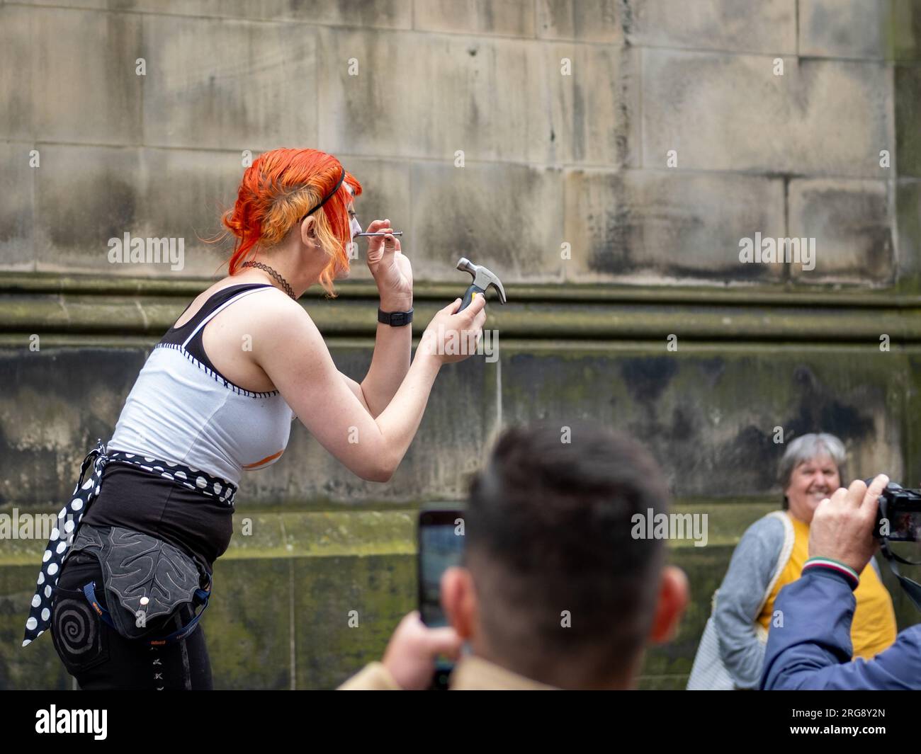 Une artiste de rue exécute son acte «Gory» de marteler des clous dans son nez, sur le Royal Mile, Édimbourg pendant le Fringe Festival, août 2023. Banque D'Images