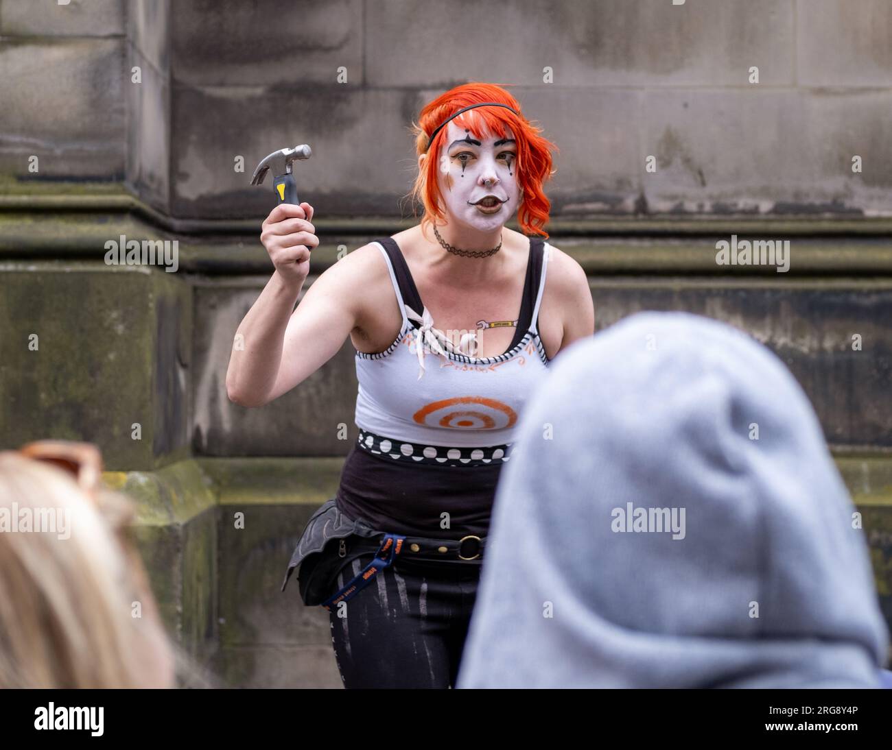Une artiste de rue exécute son acte «Gory» de marteler des clous dans son nez, sur le Royal Mile, Édimbourg pendant le Fringe Festival, août 2023. Banque D'Images