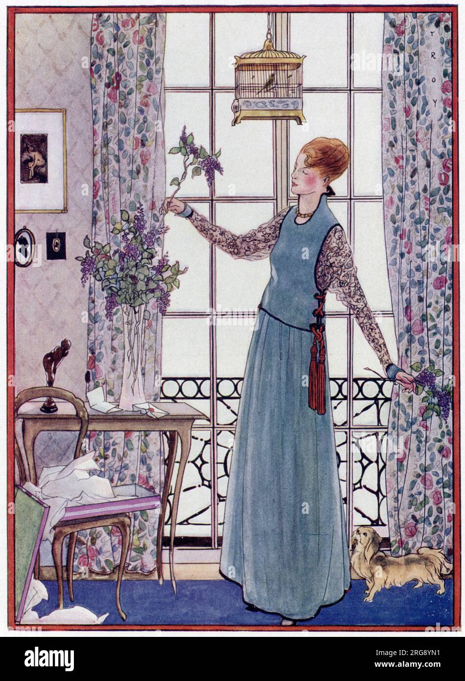 Une dame vêtue d'une robe chasuble organise artistiquement des fleurs de couleur lilas dans un vase en verre haut et étroit à tige, surveillé par son chien pekinois. Banque D'Images