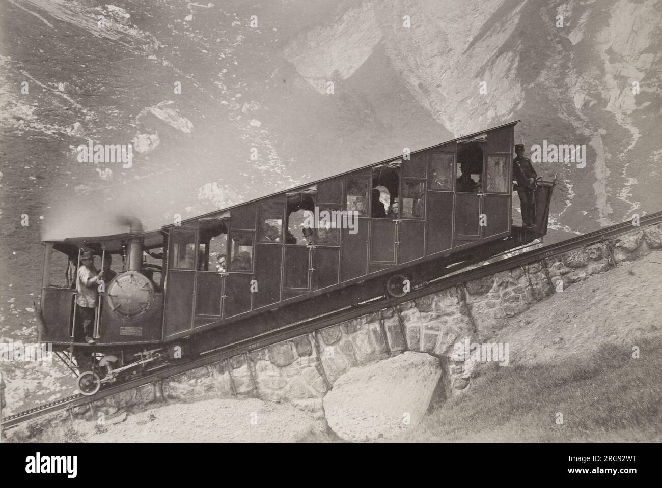 Un wagon de chemin de fer suisse à crémaillère et pignon à voie étroite, construit vers 1900, avec des conducteurs et des passagers, sur une voie en pente raide dans les Alpes. D'après les archives de Gloucester Coach and Wagon Works au Gloucester Record Office. Banque D'Images