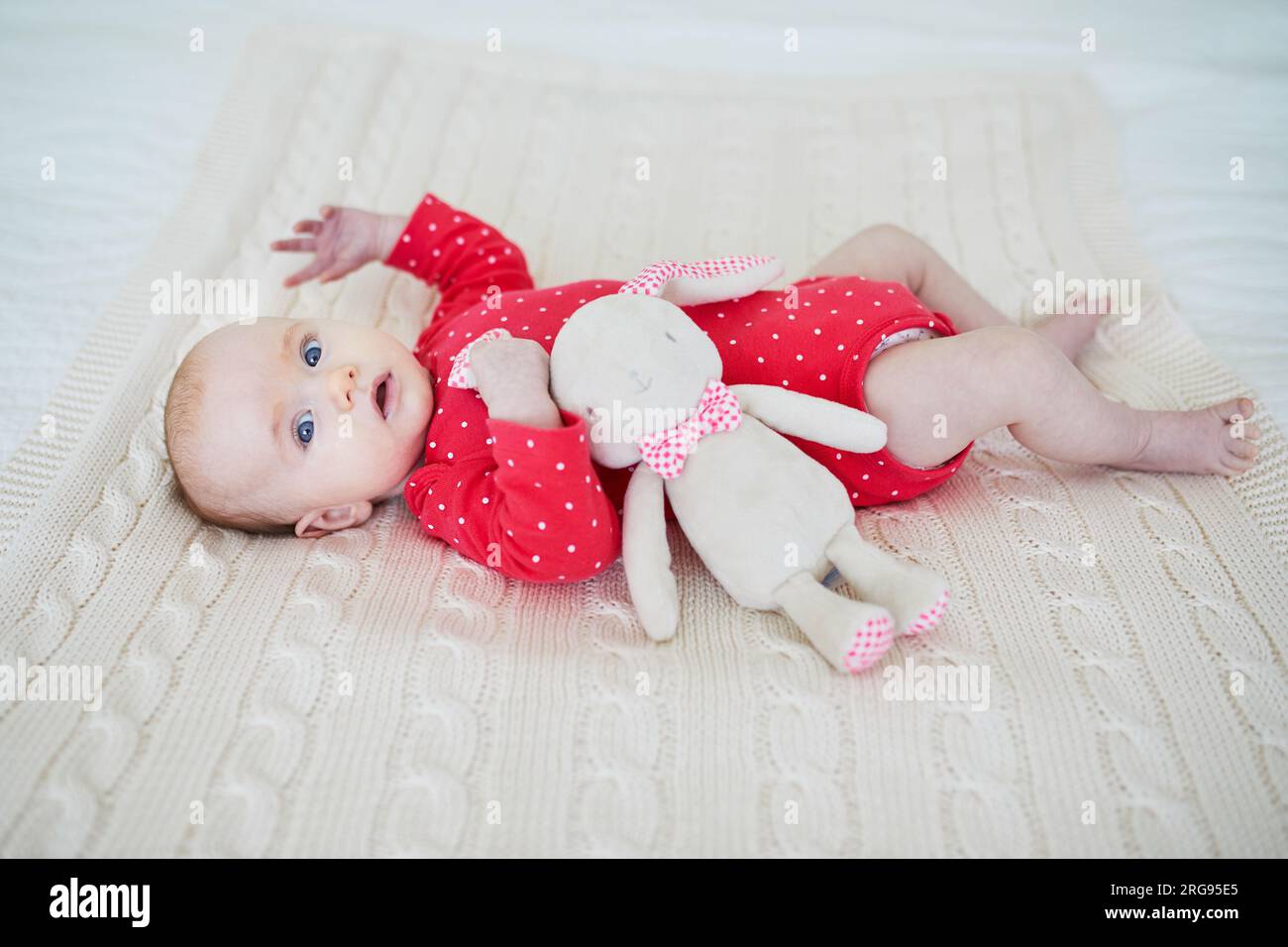 Petite fille tenant un lapin en peluche. Objet de confort pour nourrisson. Nouveau-né avec jouet préféré Banque D'Images