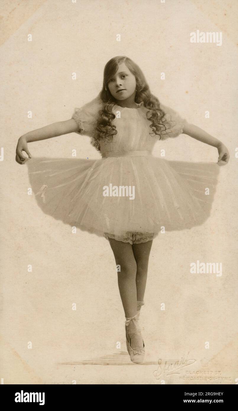 Une jeune Ballerina avec de longs cheveux courbés sur le point, tenant son tutu - portrait de studio. Banque D'Images