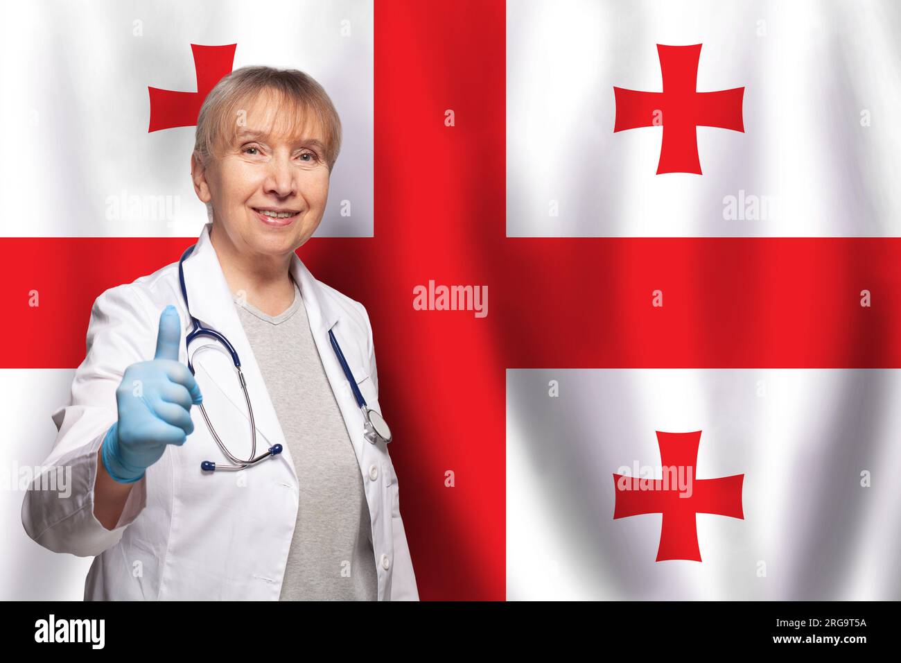 Femme médecin mature souriante géorgienne tenant le stéthoscope sur le drapeau de fond de Géorgie Banque D'Images