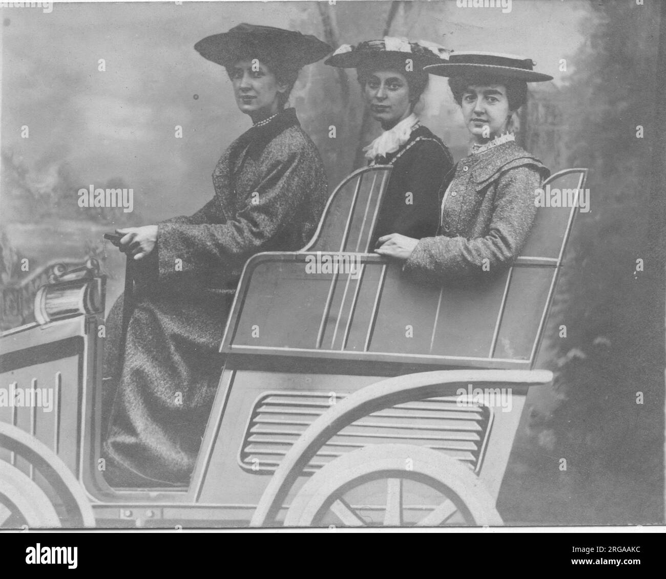 Trois dames posant pour une photo de studio dans une fausse voiture. Banque D'Images