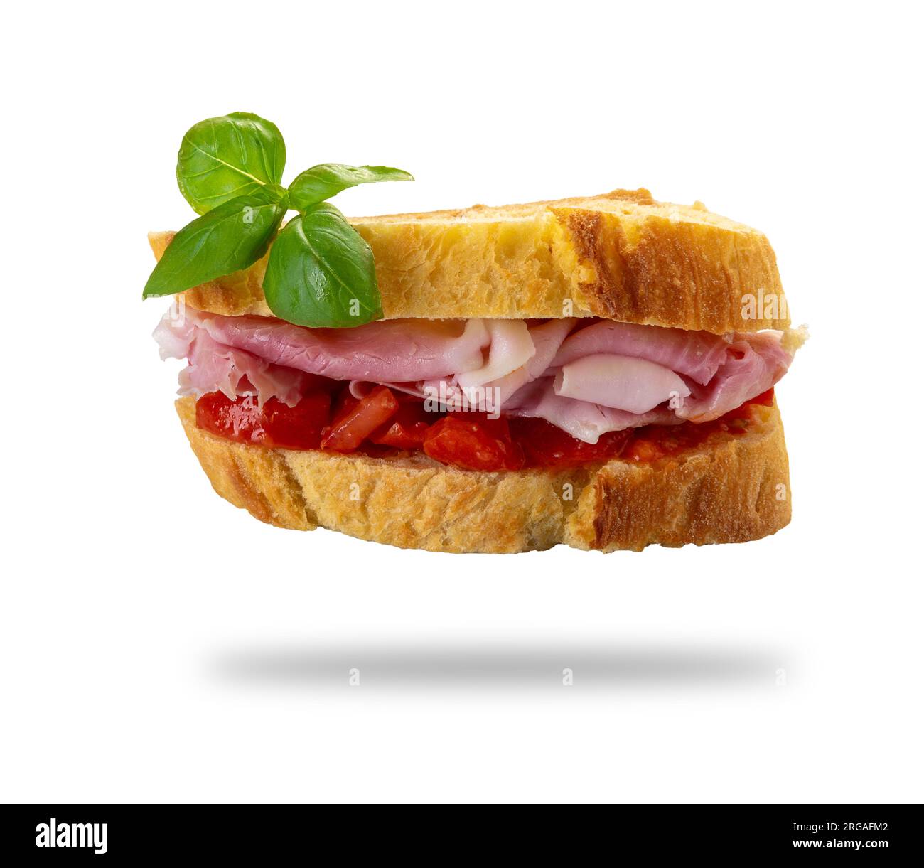 Sandwich jambon et tomate entre deux tranches de pain de semoule de blé dur avec des feuilles de basilic, isolé sur blanc avec chemin de coupe inclus Banque D'Images