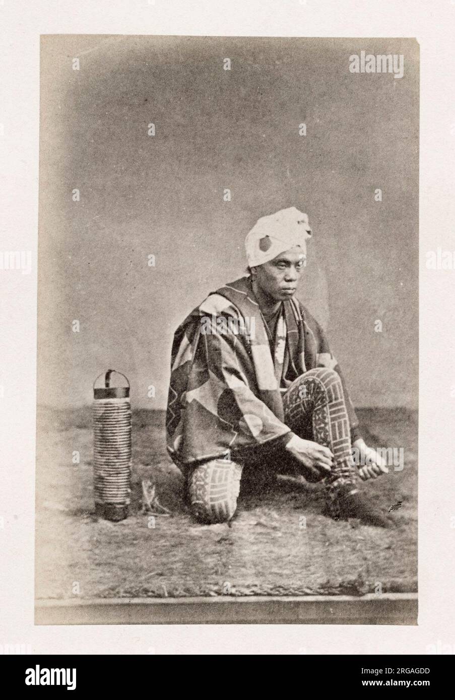 Photographie du XIXe siècle - Portrait photographique du Japon, probablement l'œuvre du photographe japonais Shimooka Renjo - homme avec lanterne nouant des lacets. Banque D'Images
