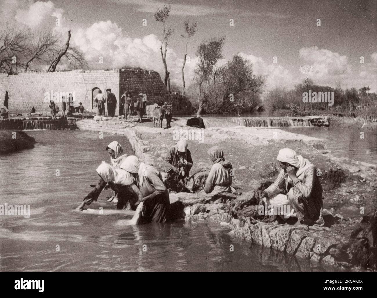 1943 Moyen-Orient Syrie - scène à Alep - femmes lavant des vêtements dans une rivière Photographie par un officier de recrutement de l'armée britannique stationnée en Afrique de l'est et au Moyen-Orient pendant la Seconde Guerre mondiale Banque D'Images