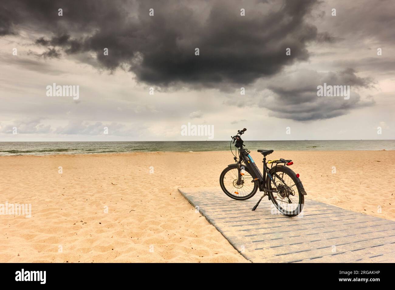 Vélo garé sur la plage de l'Iptique de Courlande sous des nuages sombres lors d'un tour à vélo de la Pologne Banque D'Images