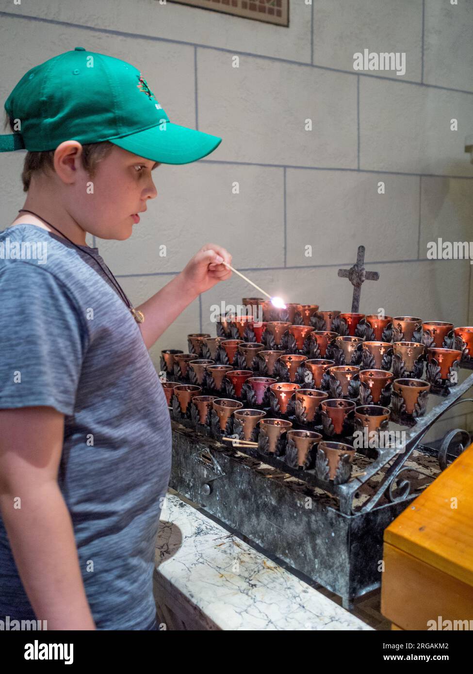 Un garçon allume une bougie de prière à l'église catholique San Miguel à Santa Fe, NM Banque D'Images