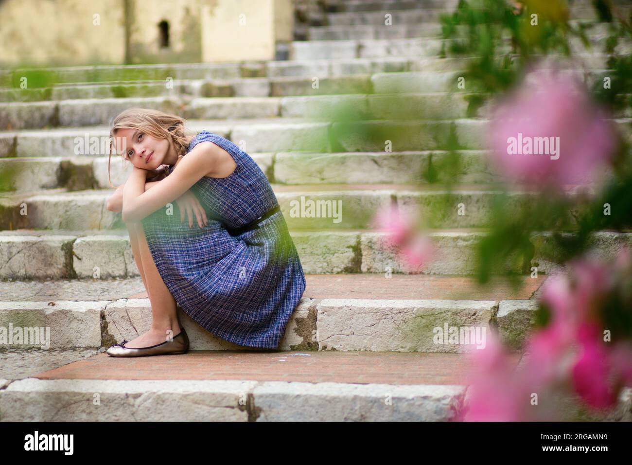 Belle jeune fille assise sur les escaliers dans une rue Banque D'Images