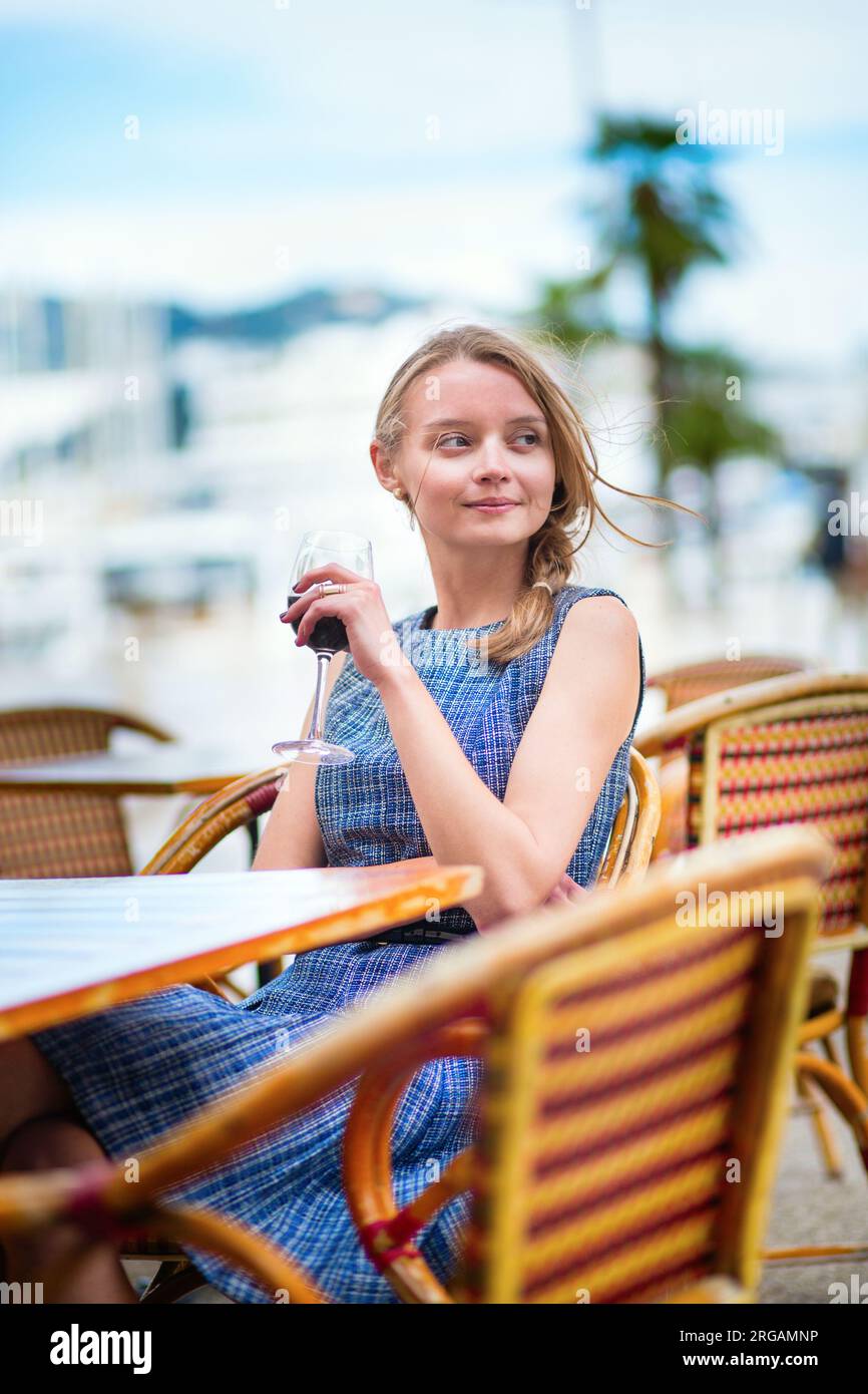 Jeune française buvant du vin rouge dans un café en plein air de Cannes Banque D'Images