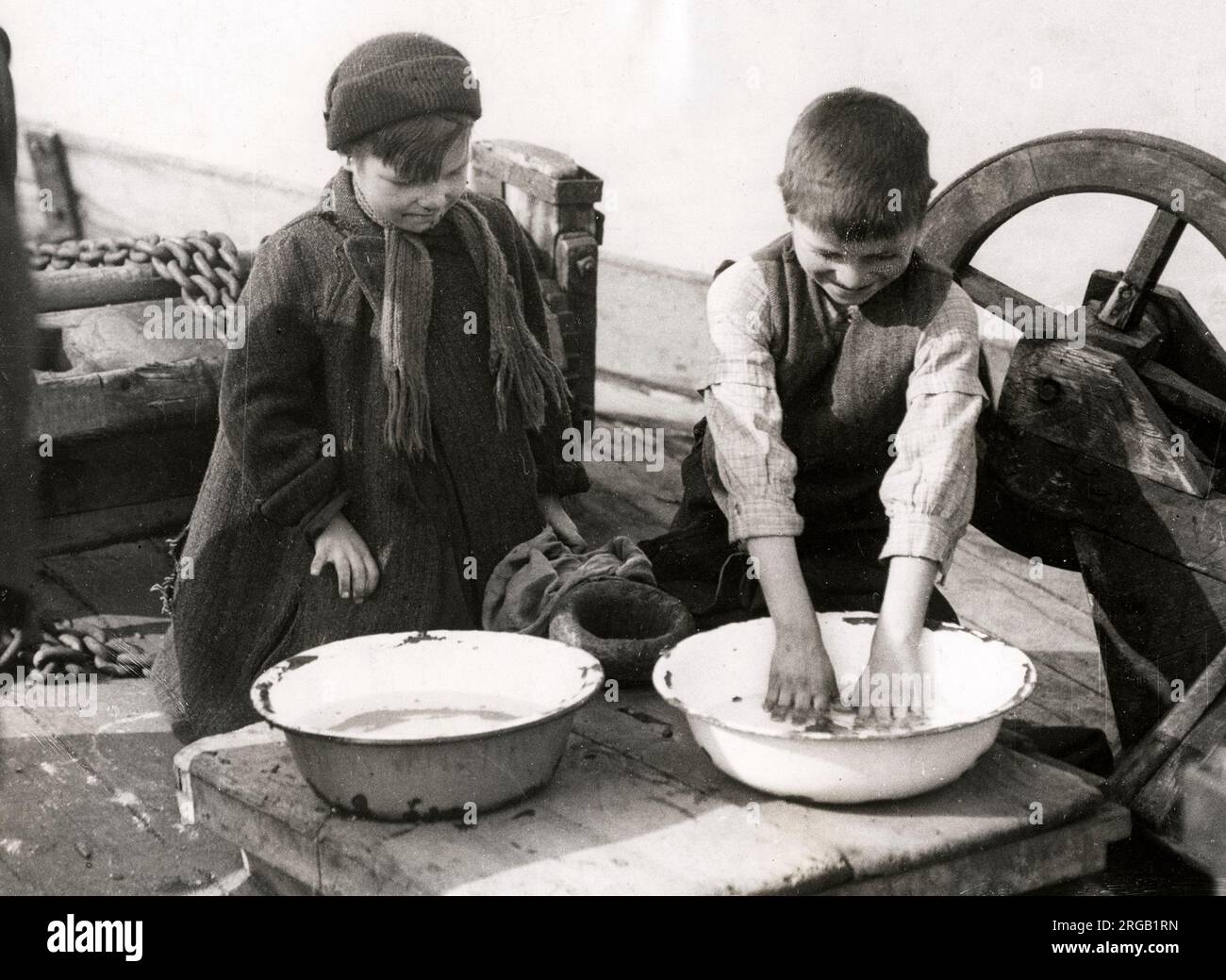 Photo de presse ancienne du début du 20th siècle - vie de famille à bord d'un bateau, histoire sociale, pauvreté, Angleterre, 1920s - les enfants se lavant dans un bol Banque D'Images