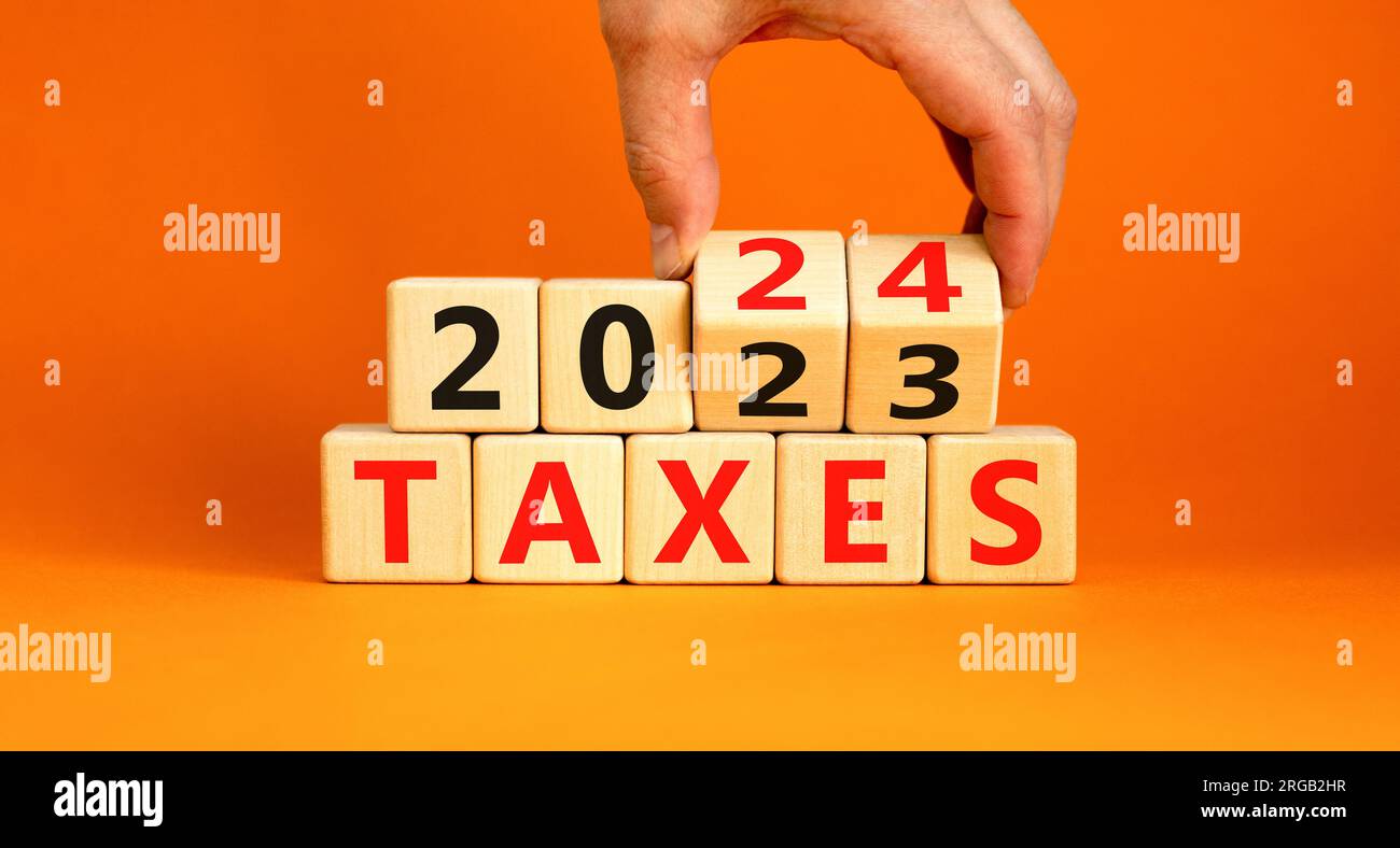 2024 taxes symbole nouvel an. Homme d'affaires tourne un cube en bois et change les mots taxes