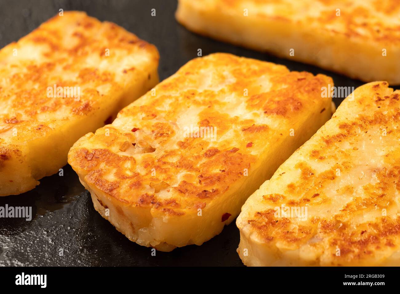 Détail des tranches frites de fromage halloumi avec du piment rouge sur une poêle noire. Banque D'Images