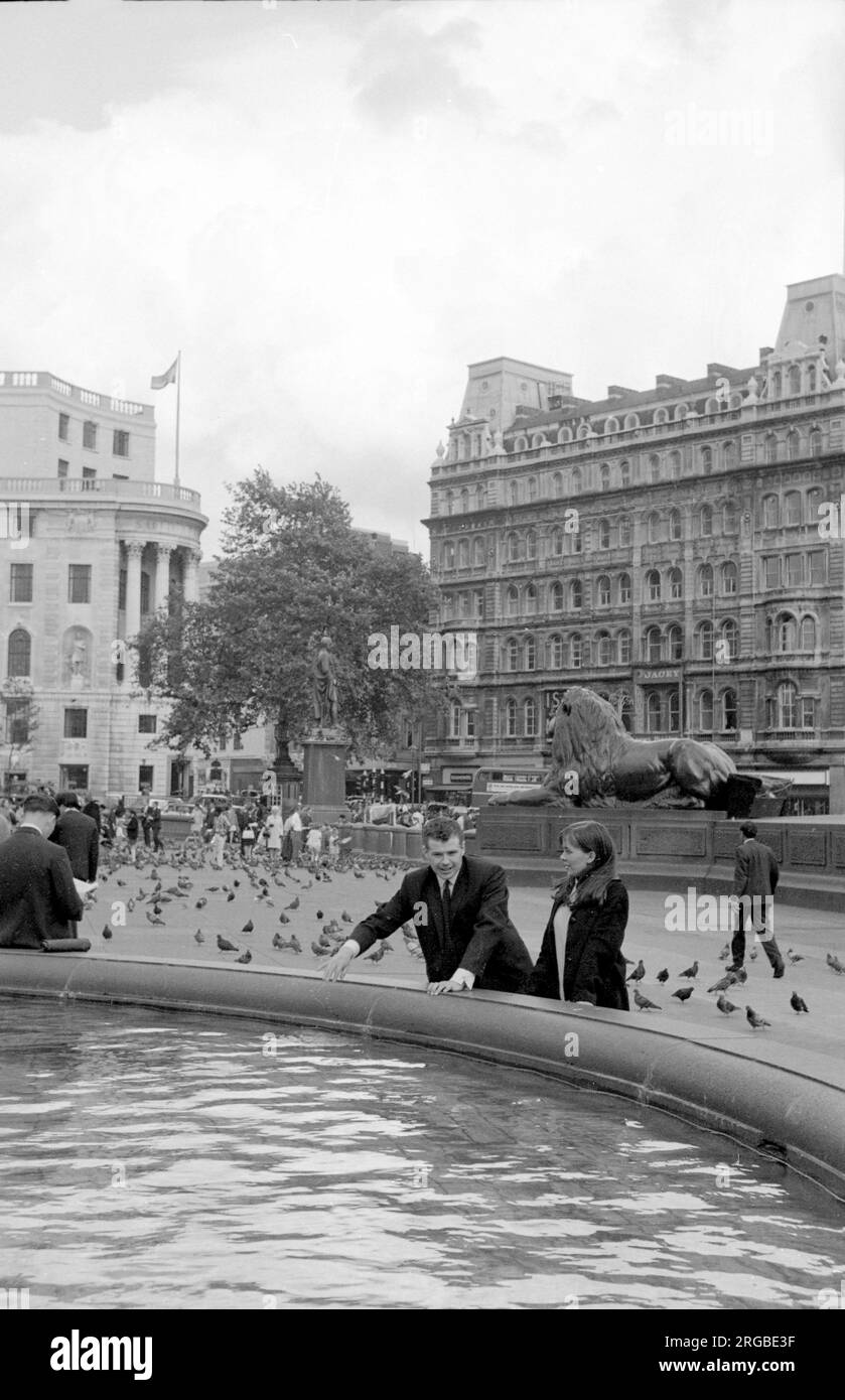 Trafalgar Square : un couple qui profite d'une fontaine, avec un Lion gardien et la statue du général de division Sir Henry Havelock, en arrière-plan. Banque D'Images