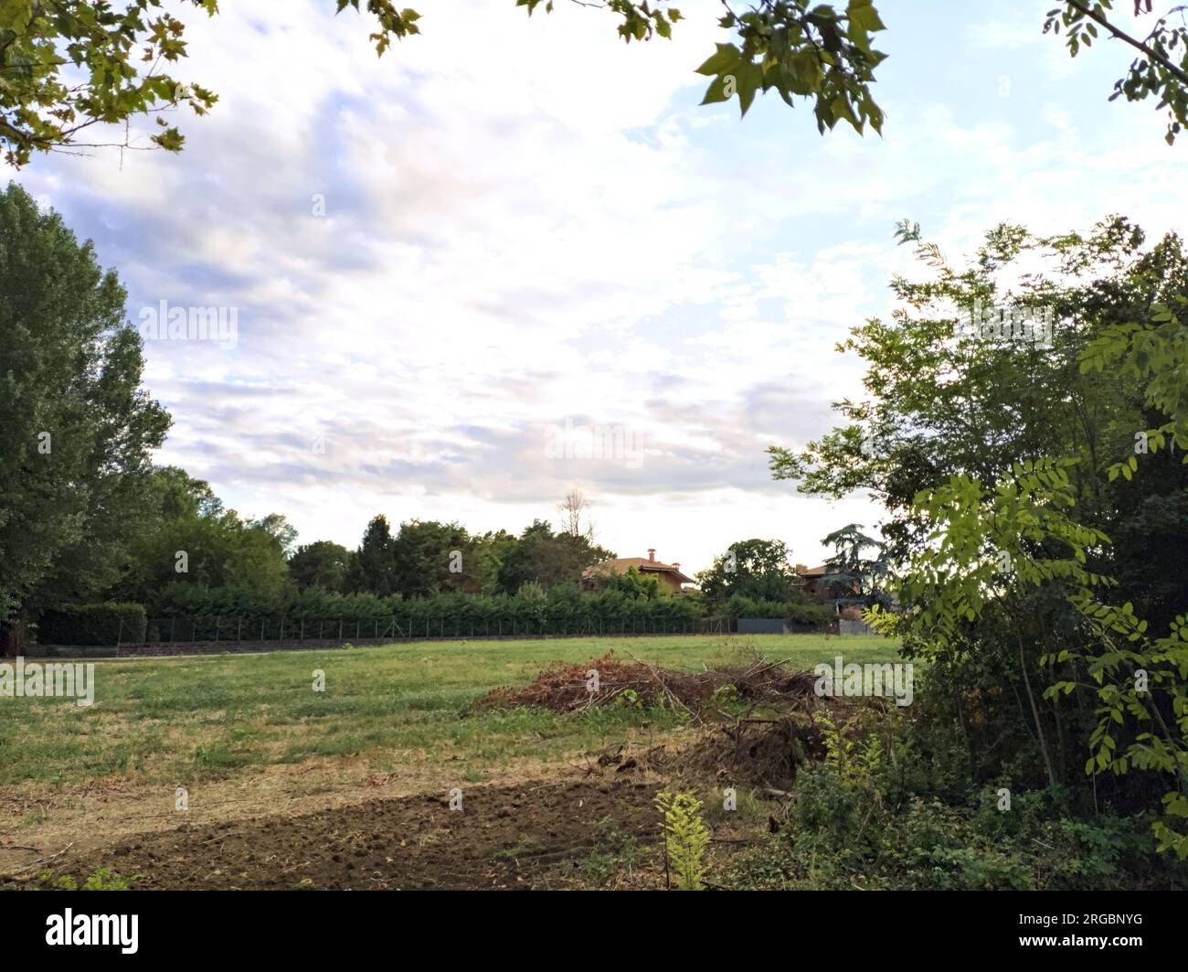 Champ et maisons bordés par une tranchée avec eau et arbres au coucher ...