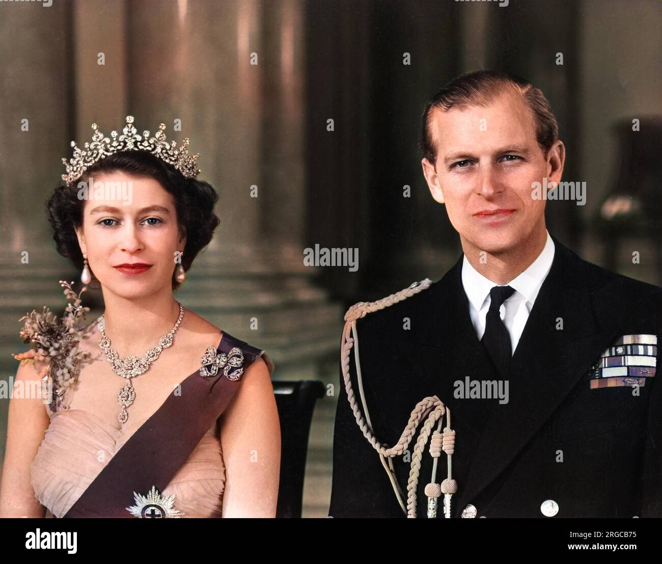 La reine Elizabeth II et le prince Philip, duc d'Édimbourg photographiés ensemble à l'entrée principale du palais de Buckingham en 1954. La Reine porte une robe de soirée en tulle jaune ornée de jets de mimosa et de broderie de pailette d'or et porte le ruban bleu et l'étoile de la jarretière. Son collier était un cadeau de mariage du Nizam de Hyderabad; le tiara était également un cadeau de mariage de la reine Marie. La broche en forme de noeud et les pendants d'oreilles sont ornés de diamants. Le duc porte l'uniforme de l'amiral de la flotte. Banque D'Images