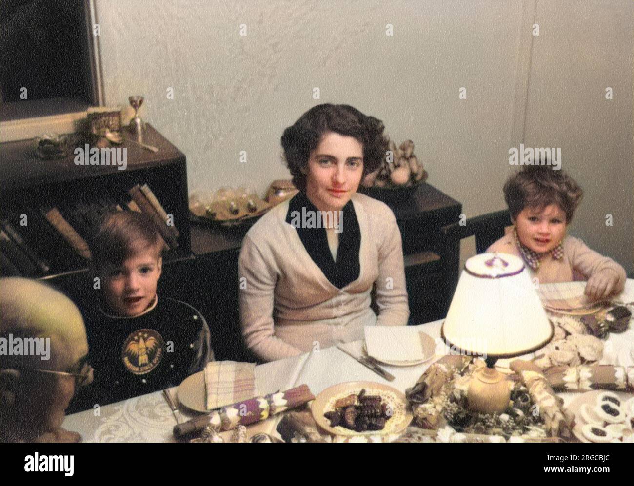 Dîner de Noël en famille - années 1950 Le jeune garçon (devant à gauche) porte son cadeau de Noël - une «tenue spatiale martienne». Banque D'Images