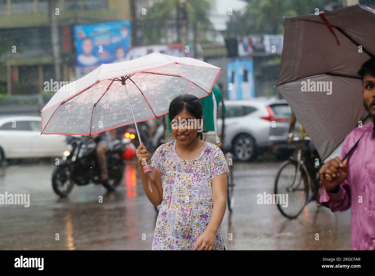 DHAKA, BANGLADESH- 8 AOÛT 2023 : une fille tient un parapluie alors qu'elle attend un véhicule pendant les pluies à Dhaka, Bangladesh, le 8 août 2023. Banque D'Images