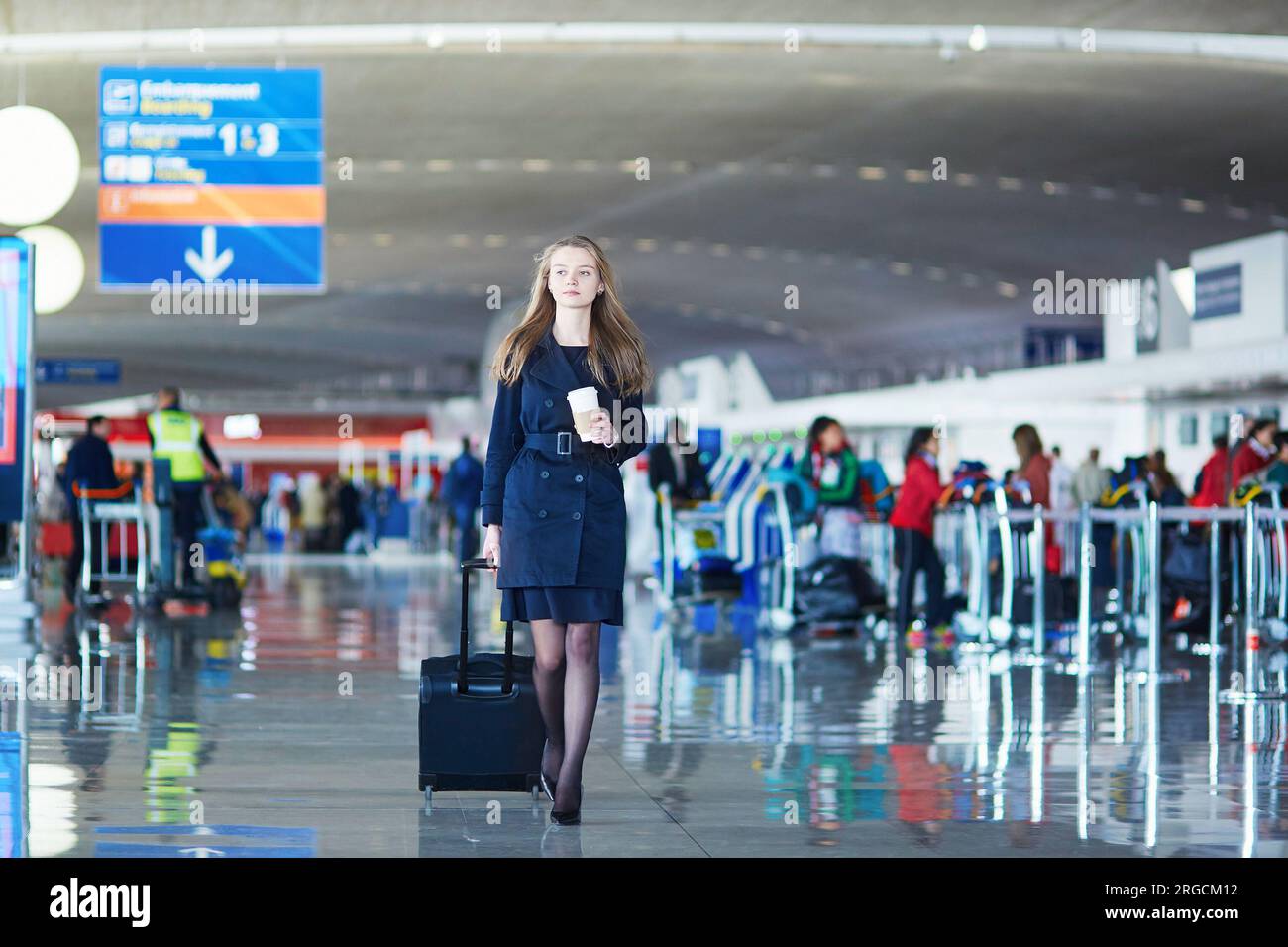 Jeune femme à l'aéroport international, marchant avec ses bagages Banque D'Images