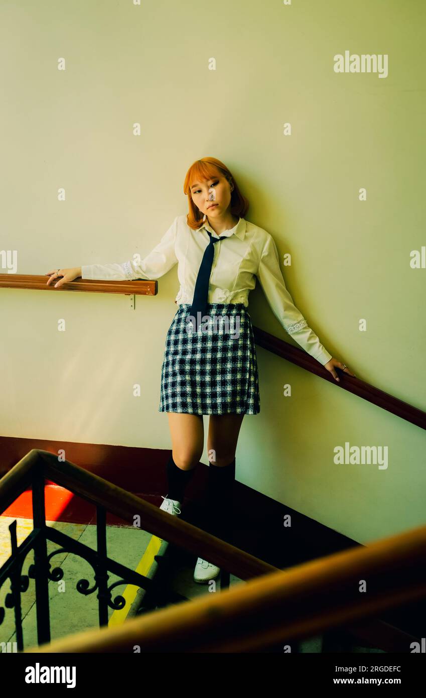 Un mignon étudiant asiatique en uniforme de gingembre se tient debout sur un escalier universitaire. Diversité, représentation et poursuite de l'éducation. Banque D'Images