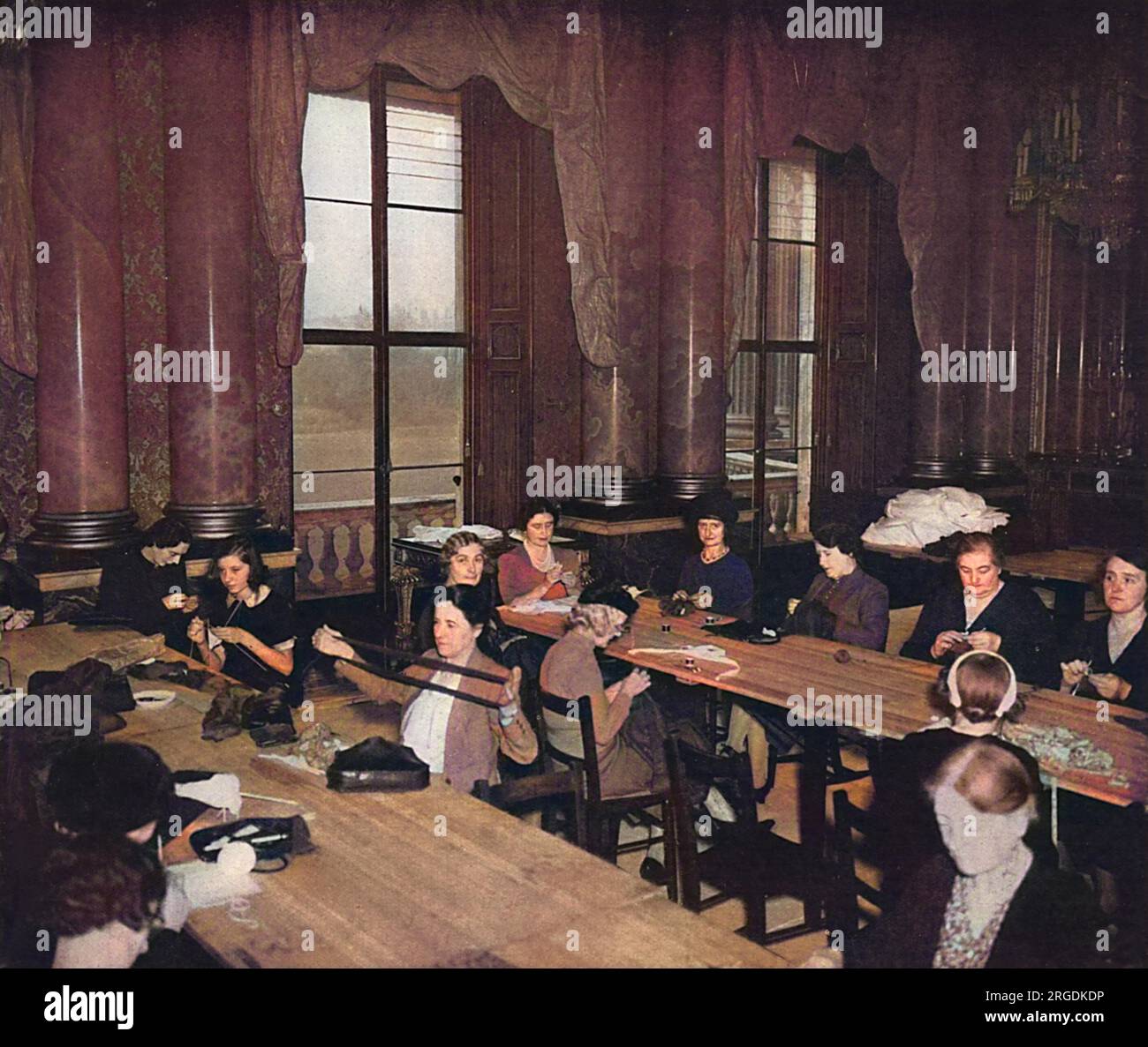 Les membres de la maison du palais et les épouses des employés des Royal Mews se sont réunis dans la salle de dessin bleue du palais de Buckingham pour l'abeille de couture de la reine Elizabeth, tenue deux fois par semaine pendant la Seconde Guerre mondiale afin de produire des vêtements et des pansements chirurgicaux pour la Croix-Rouge. Les femmes peuvent être vues assis à des tables à chevalets dans ce qui est l'un des plus beaux des appartements d'État du palais de Buckingham, et était à l'origine la salle de bal de la reine Victoria. Banque D'Images