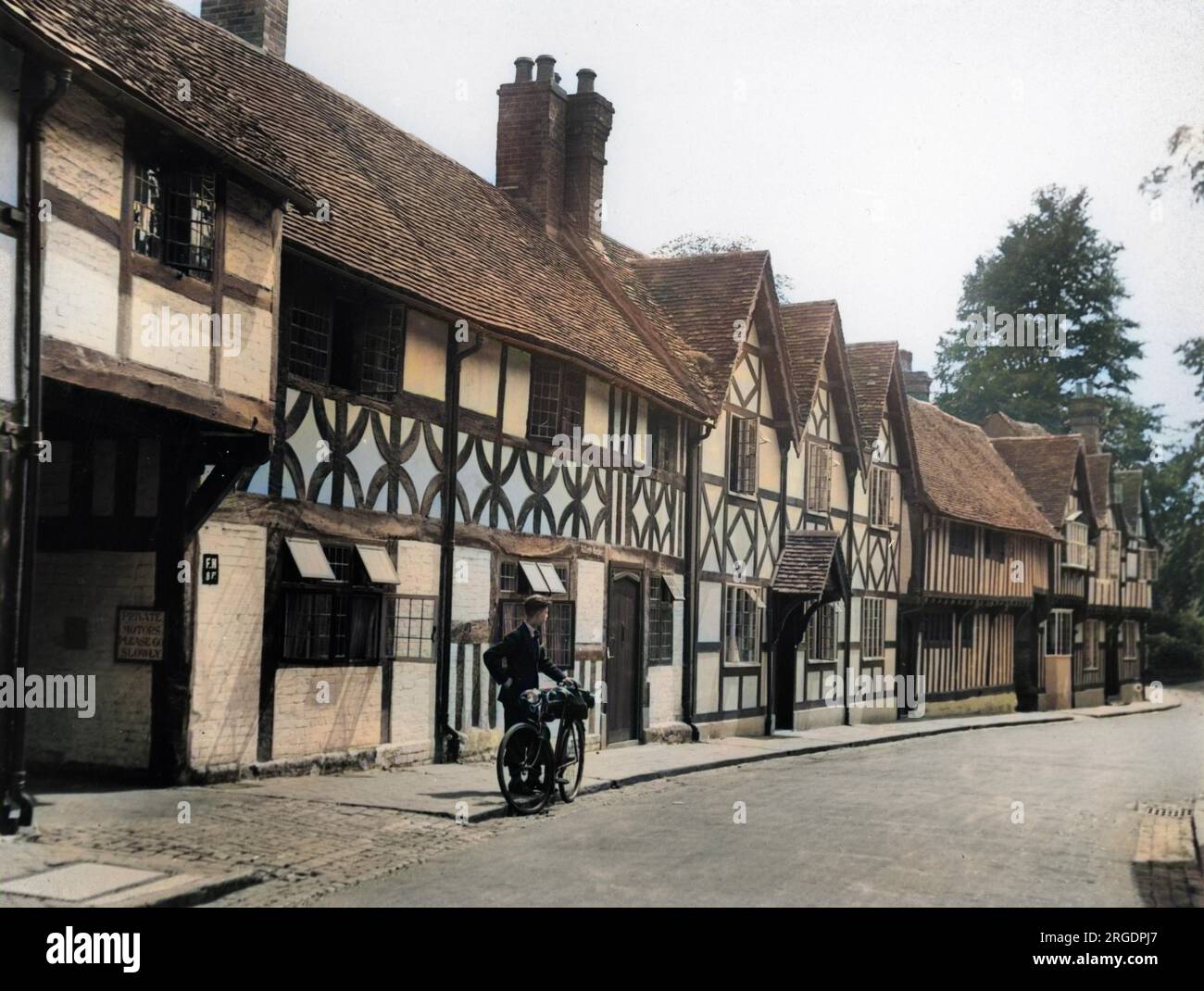 Mill Street, Warwick, avec un cycliste admirant une rangée de maisons à colombages Tudor, un aperçu de l'Angleterre de Shakespeare. Banque D'Images