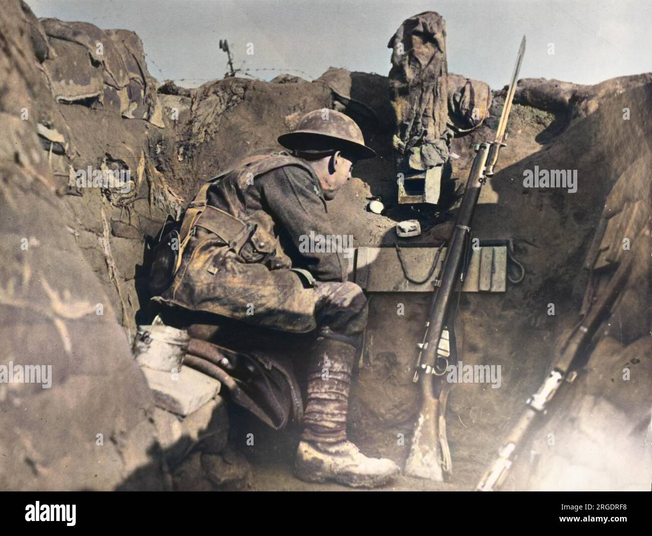Un soldat dans un poste de garde dans une tranchée utilisant un périscope camouflé pour surveiller le front britannique en France pendant la première Guerre mondiale en 1917. Il a un fusil Lee Enfield Mk III à côté de lui. Banque D'Images