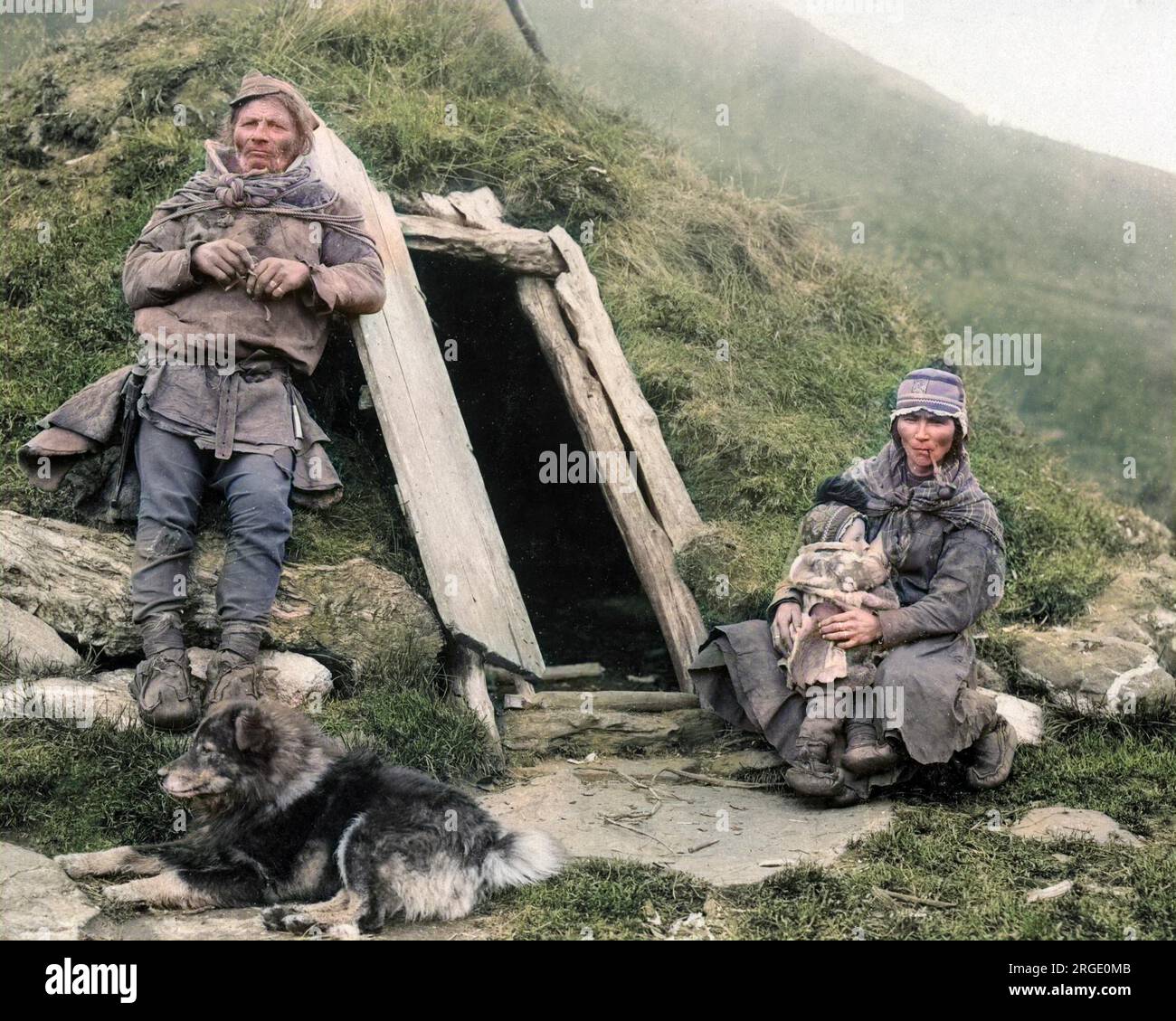 Sami couple, bébé et chien devant leur maison. Ils proviennent de la région arctique de Sapmi, qui couvre les parties septentrionales de la Scandinavie et de la Russie. Banque D'Images