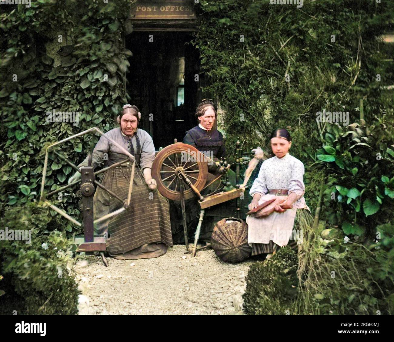 Deux femmes et une fille assises à l'extérieur du bureau de poste avec une roue tournante et d'autres équipements, Écosse. Banque D'Images