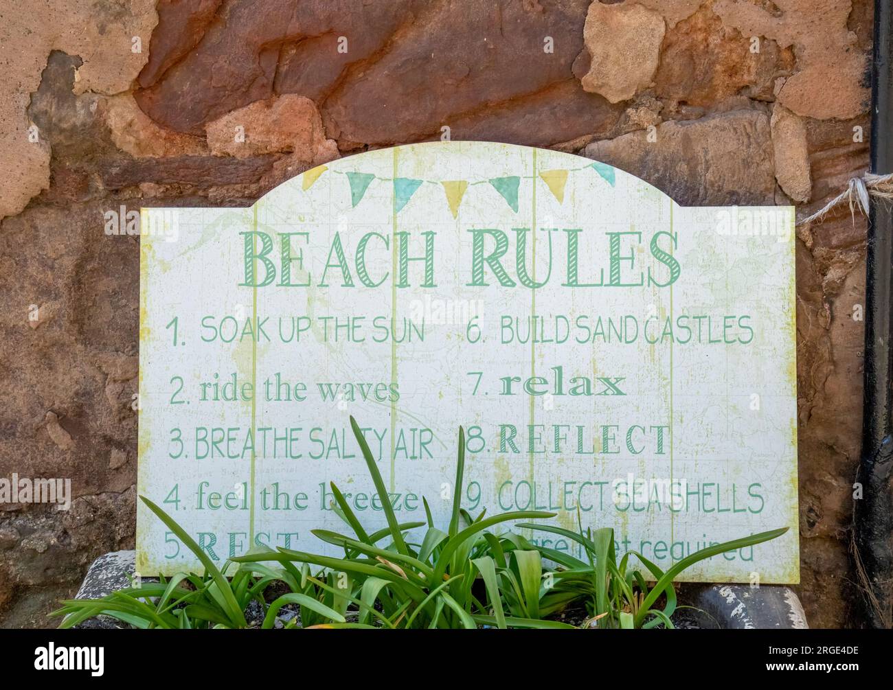 Signe drôle sur un mur dans un village côtier avec des règles de plage humoristiques Banque D'Images