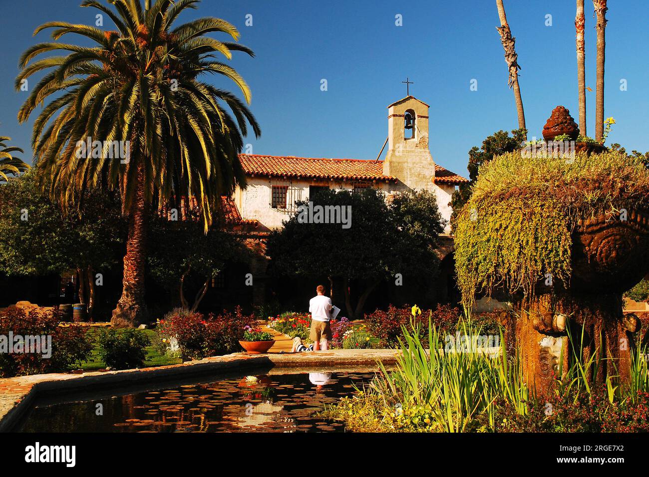 Les gens se promènent dans les jardins fleuris historiques de la mission San Juan Capistrano en Californie par une journée ensoleillée Banque D'Images