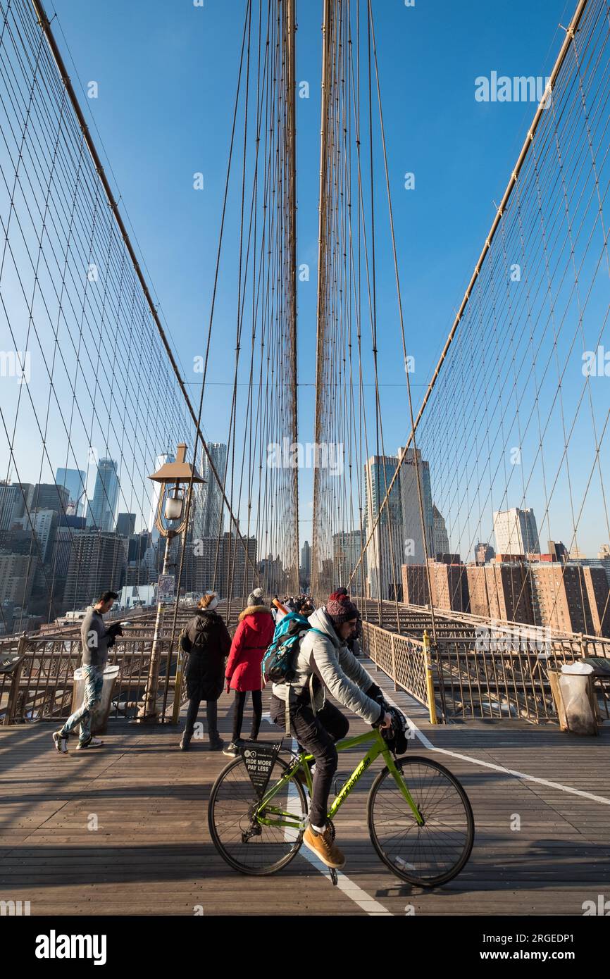 Manhattan, NY, États-Unis - 11 décembre 2018 : un cycliste passe la piste cyclable du pont de Brooklyn, avec un groupe de touristes marchant derrière Banque D'Images